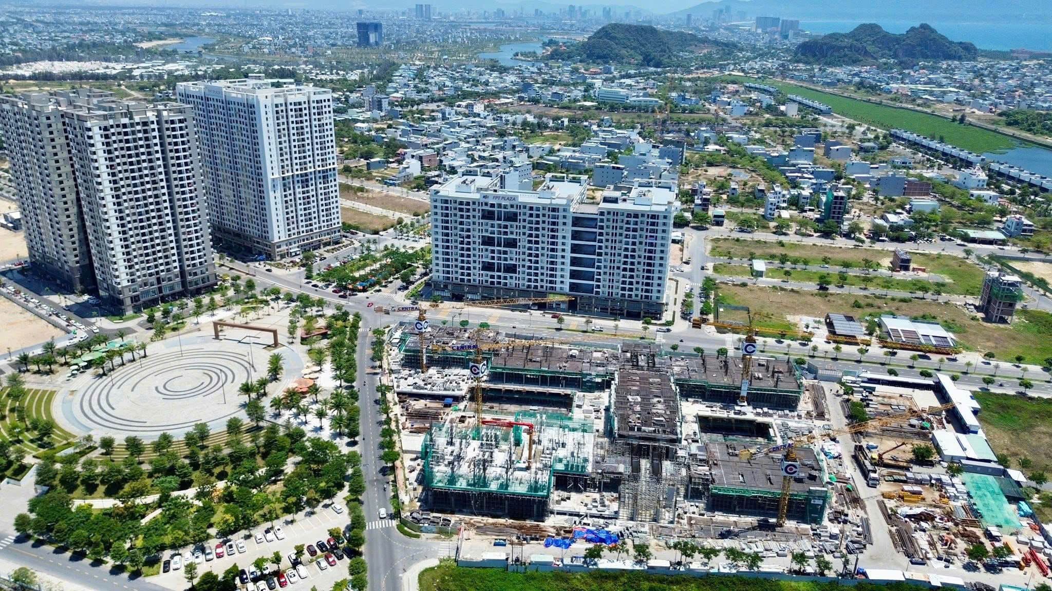 Aerial view of high-rise apartments and construction sites in a growing riverside urban district