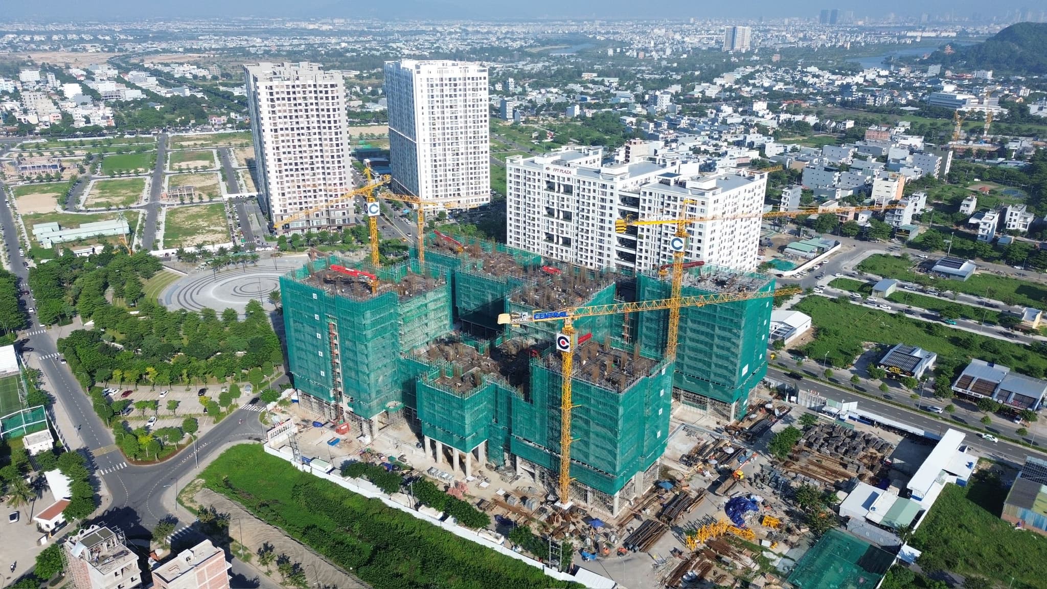 Aerial view of high-rise apartment construction with tower cranes in a modern urban neighborhood