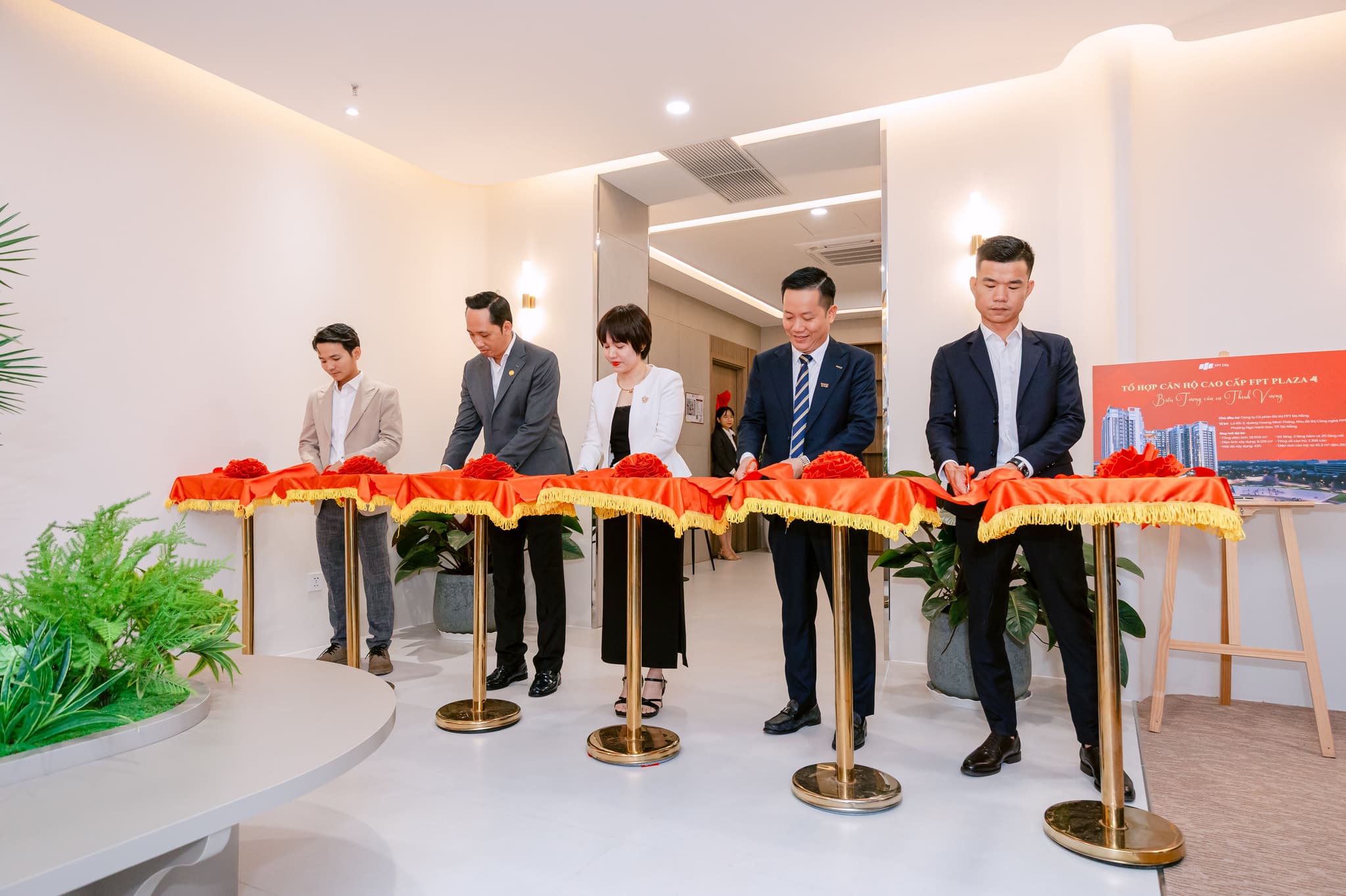 Group of five officials cutting a ribbon during a formal opening ceremony in a modern interior setting.