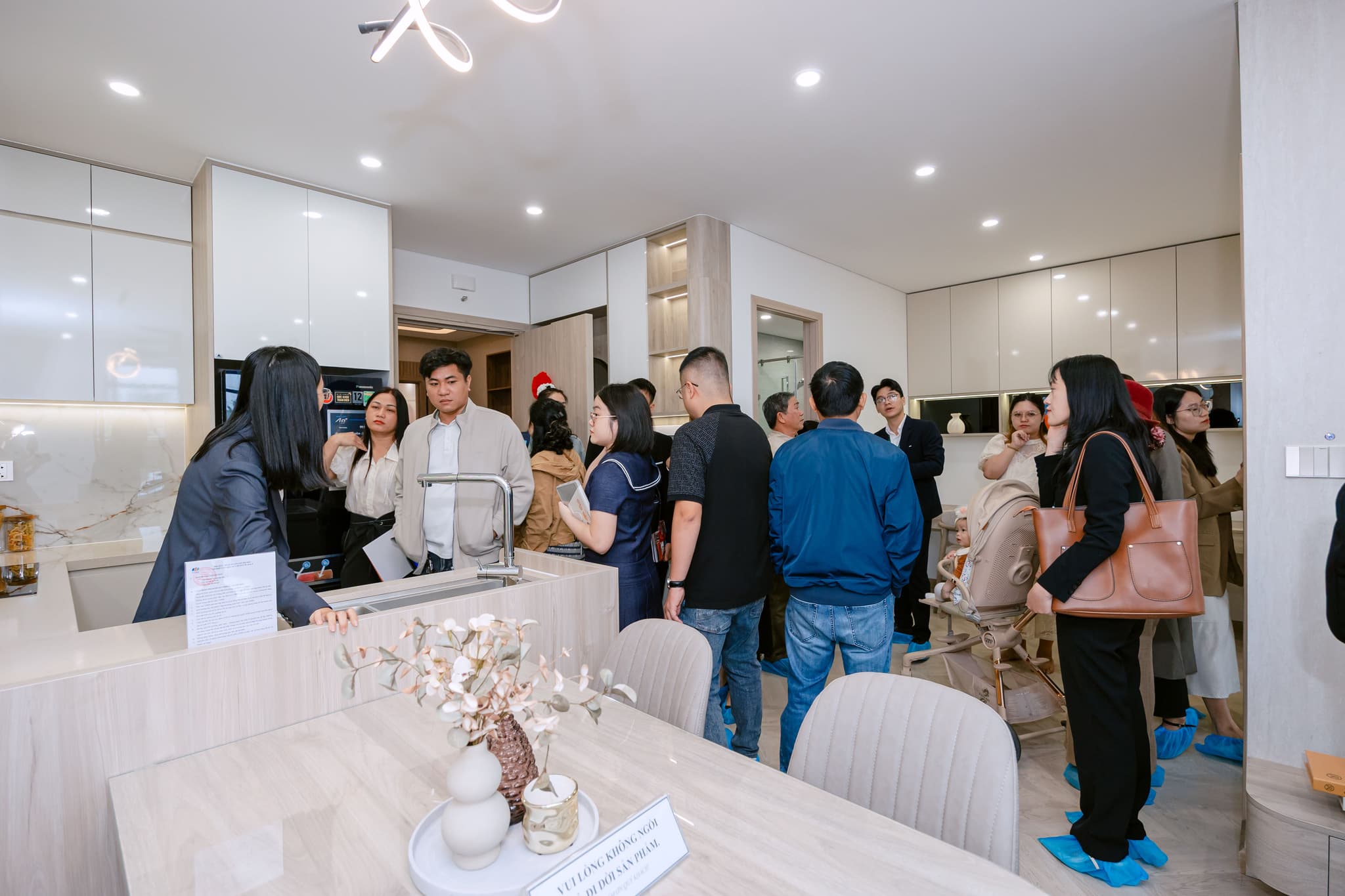 A lively group of people interacting in a modern kitchen space, showcasing a real estate or interior design event.