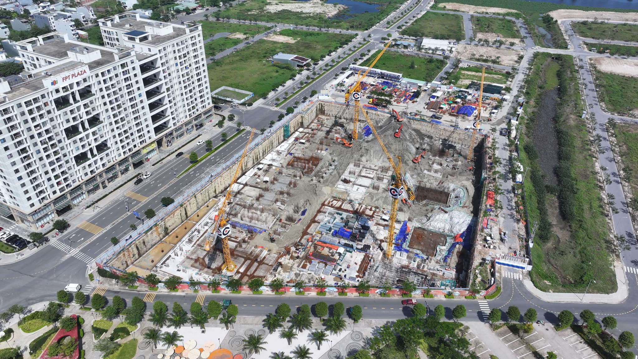 Aerial view of an urban construction site with tower cranes beside modern high-rise apartments.